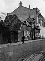 Ragvaldsgatan 21 söderut mot Södra Latins läroverk. Två pojkar leker vid porten till gården. Huset revs 1912. Södra Latin invigdes 1891 och är idag Södra Latins gymnasium.