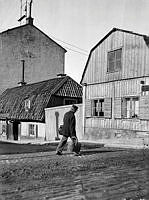 En man passerar vid Ölandsgatan 17 C. Vy västerut från Götgatan. Motsvarar nuv. läget för Ringens köpcentrum vid Götgatan 100.