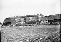 Utsikt från Odengatan mot Karlbergsvägen 32-34. I förgrunden en tobakslada, komministerboställe och en bondgård i kv. Resedan, där Vasa Real uppfördes 1916-1927.