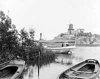 Utsikt från Barnängsbryggan mot Danviksklippan med kvarnen Klippan. Ångslupen Nackanäs ligger på Hammarby sjö. Roddbåtar i förgrunden.