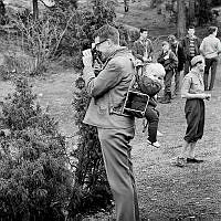 Fotograferande man med sitt barn i en bärstol på ryggen.