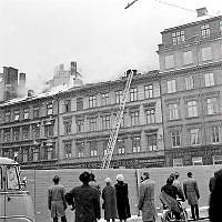 Grupp av åskådare betraktar släckningsarbete på taket till Arvid Nordquist HAB, Biblioteksgatan 27.