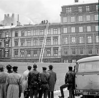 Människor som betraktar släckningsarbete på taket till Arvid Nordquist HAB, Biblioteksgatan 27.