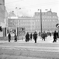 Folk som betraktar släckningsarbete på taket till Arvid Nordquist HAB, Biblioteksgatan 27. Korsningen Sturegatan - Humlegårdsgatan.