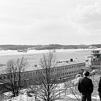 Utsikt från Ranhammarshöjden över Bromma flygplats. Flygplan från Linjeflyg på väg upp i luften. Åskådare i förgrunden.