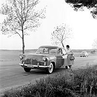 Ford Zephyr parkerad vid kanten på en landsväg. En kvinna står och samtalar med föraren.