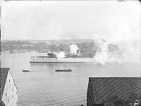 Den amerikanska pansarkryssaren USS Baltimore på väg in mot Stockholm. Vy från Stigberget norrut över Saltsjön med Skeppsholmen i fonden.