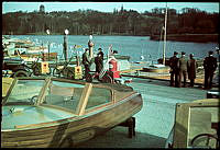 Kungliga Motorbåtsklubbens hamn vid Djurgårdsbrunnsviken. Upplagda och förtöjda motorbåtar. Grupper av män som betraktar motorbåtar.