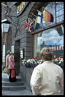 Skeppsbron 44. Restaurangen Zum Franziskaner. Människor utanför restaurangen. Blomsterplantering och nationsflaggor.