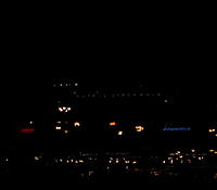 Norrmalmstorg mot Citypalatset. Kvällsbild; bara fasadens ljusreklam och torgets gatlyktor syns.
