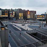 Från gångbron i Stockholmsterrassens norra del mot Sergels Torgsrondellen. Fasadreklam i kv. Skansen och Fyrmörsaren. Fontänen under byggnad.