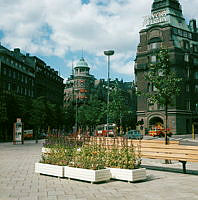 Blomsterlådor och parkbänkar på Engelbrektsplan. Till höger försäkringsbolaget Trygg-Fylgias byggnad i kv. Bössan.