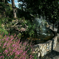 Millesgården på Lidingö; Skulpturparken. Damm med skulpturer, blommor och små fontäner.