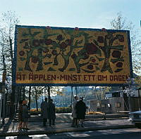 Stor skylt med mosaik av äpplen uppställd i Kungsträdgården vid Hamngatan. Trädmotiv. Text: 