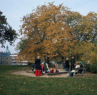 Lekande barn med mammor vid sandlåda i Observatorielunden. I fonden ses tornet av Gustaf Vasa kyrka.