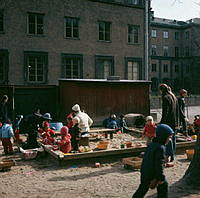 Barn och vuxna i sandlådan vid parkleken i Observatorielunden. I bakgrunden Handelshögskolan.