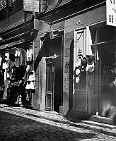 Utanför butikerna vid Västerlånggatan 69 hänger kläder och hattar till försäljning.