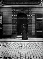 En kvinna står utanför porten till Stora Nygatan 19. Skylt med texten Lars Monten.