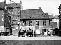 Butiker och verkstäder vid Oxtorget 2 på Oxtorgets norra sida. Husen i fonden ligger vid Lutternsgatan 24 (nu Kungsgatan). Här ligger idag Södra Kungstornet vid nuvarande Oxtorget 8.