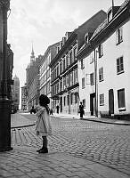 En flicka står vid korsningen av David Bagares Gata och Regeringsgatan. Fotografi mot väster.