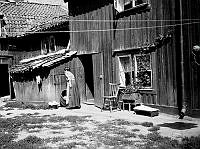 Gårdssidan vid Styrmansgatan 20 (nuvarande 16). En kvinna står bredvid en balja med tvätt och ett träkar.