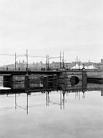 Kungsbron sedd från Kungsholms Strand. Svängbro i stålkonstruktion byggd 1881, elektrifierad 1906, riven 1944. Vasastaden i fonden.