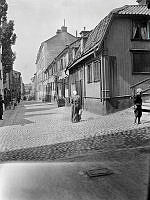 En kvinna går Tavastgatan västerut från Timmermansgatan. T.h. Tavastgatan 30-34. Tavastgatan 32, lumpaffären, revs 1910.