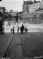 En man och några barn står vid Erstagatan 14. Erstagatan och Erstagatans trappor norrut vid korsningen med Folkungagatan.