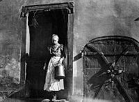 En kvinna står i dörröppningen till gården vid Bondegatan 4, nuvarande 10. Dörren av järn leder till källaren.