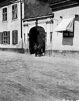 Värmdögatan 55. Vid porten mot gården står två pojkar vid en skrinda. Nuvarande Malmgårdsvägen 55.