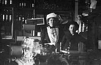 Interiör från Livsmedelsaffär på Götgatan 77 omkring år 1915. På bilden syns fru Augusta Norgren tillsamman med sonen Harry.
