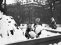 Barn som leker med snö vid Molins fontän i Kungsträdgården.