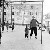 Man med barn på lekplats som spolats till skridskobana, Enskede.