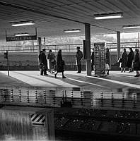 Väntande resenärer vid Gamla Stans tunnelbanestation. På perrongen en choklad -, frukt - och tobaksautomat.