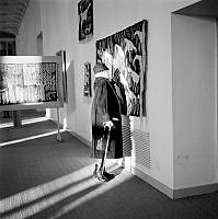 Äldre dam med käpp betraktar på nära håll ett textilt verk på utställning i Moderna museet.