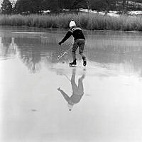 Pojke spelar bandy på blankfrusen sjö.