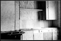 Interiör med plywoodbeklädnad i kök samt gasspis och diskbänk i hus i Enskede småstugeområde.