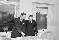 Två män tittar på en ritning på ett nytt bostadsområde på Lidingö.