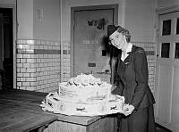 Regeringsgatan 14. Fröken Birgit Löfberg vid American Overseas Airlines bredvid en tårta, bakad på Oscar Bergs hovkonditori.