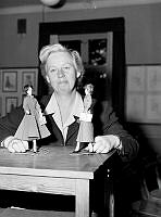 Rektor Anna Kjederqvist på yrkesskola för klädsömnad, med gesällprover från 1948 och 1949 (en Molyneuxmodell t.v. och en Diormodell t. h.) kopierade i små dockor.