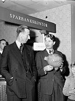Kungsgatan 18, Kungshallen. Sparfrämjandets utställning. En man håller i Sparbankens klassiska sparbössa, en spargris.