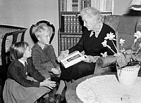 Fru Ester Sterner visar barnbarnen Annika och Jan en bok om Gustaf V på hans dödsdag.