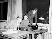 Holländargatan 32. Internationell studentkonferens i Stockholms Högskolas kårhus. Två unga män och en kvinna vid en skrivmaskin och en bandspelare.