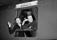 En kvinna och en man vinkar från ett tågfönster på tåg mot Malmö.