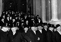 Riksdagspolitiker i rockar och höga hattar tågar upp till Slottskapellet och 1951 års riksdagsöppnande.