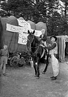 Huddingevägen. En pojke rider på en häst på Cowboy Camp. En ridtur kostar 50 öre. På tältvagnen står det 