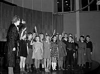 Ringvägen 58, Eriksdals folkskola. Barn demonstrerar berättande sång tillsammans med sin lärarinna, under småskollärarinneförbundets kurs i sångundervisning.