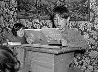 Interiörbild med läsande pojke i en skolbänk i den första skolan för romer som just öppnats i familjen Taikons tält vid romernas läger vid Lilla Sköndal i Gubbängen.
