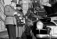 Polismännen Axelsson och Remblad från Gengaspolisen undersöker ett gengasläckage i en bil med hjälp av en koloxidindikator. T.h. Ingenjör Sieurlin från Gengasbyrån.