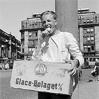 Tegelbacken. En ung glassförsäljare äter glass, med en glasslåda från Glace-Bolaget (GB) på magen. Centralpalatset i bakgrunden.